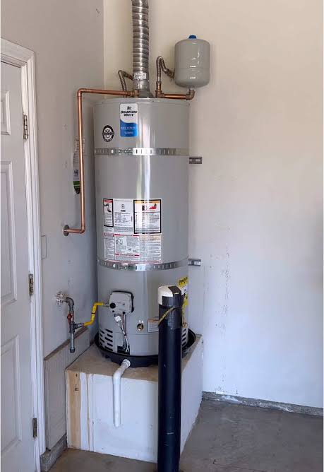 Conventional gas tank water heater installed in a garage with copper piping, expansion tank and vent